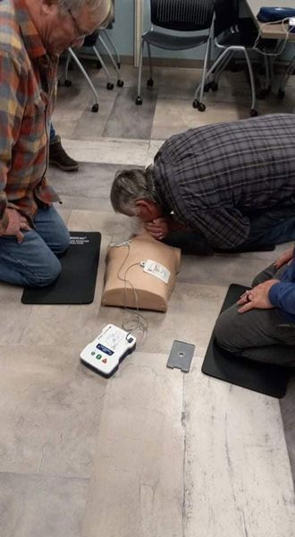A man is kneeling on the floor with his head on a mannequin.