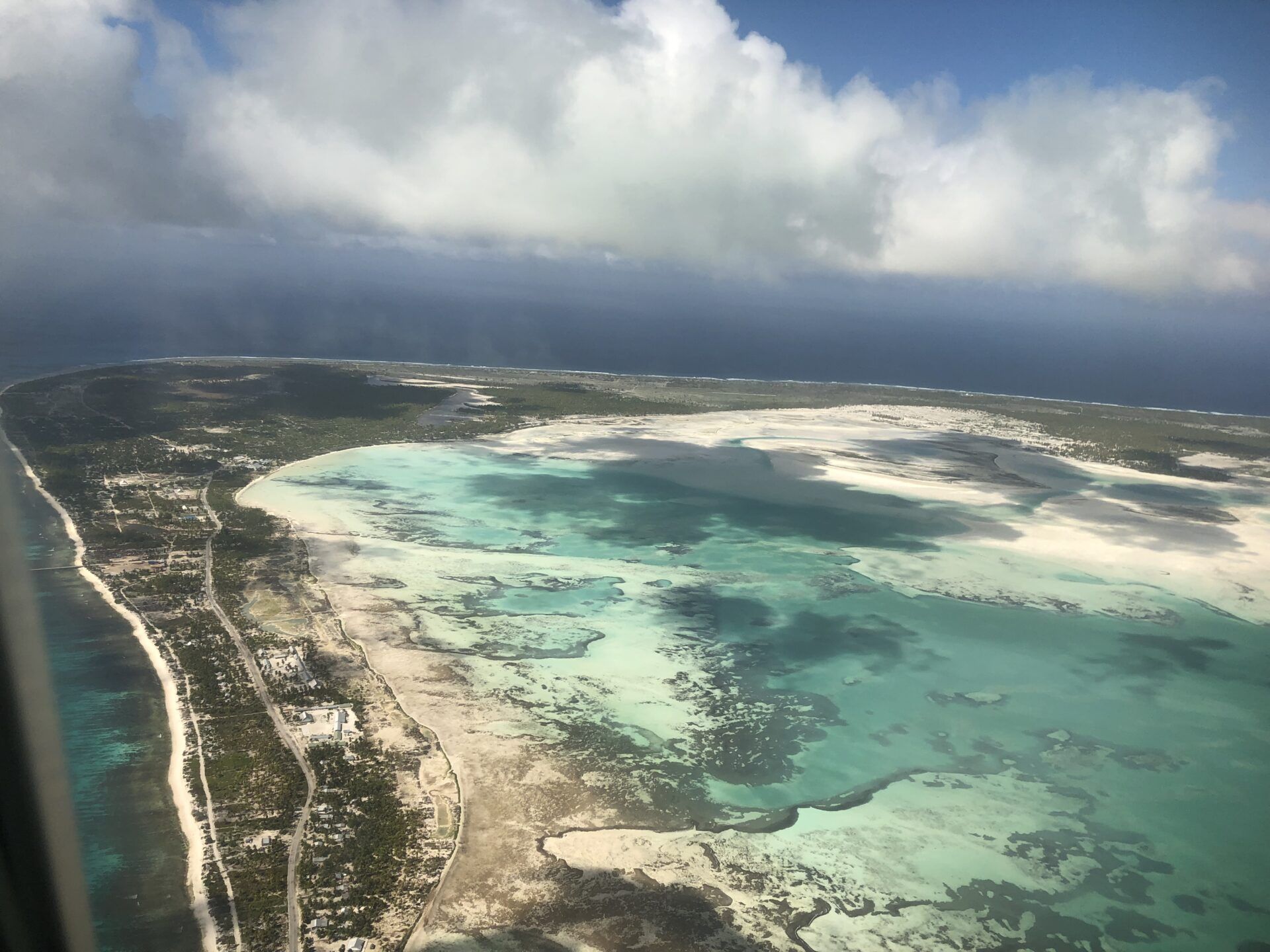 Aerial view of a tropical island, featuring a turquoise lagoon bordered by a white sand beach and lush green vegetation.