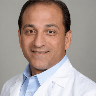 Portrait of a smiling doctor in a white coat against a gray background