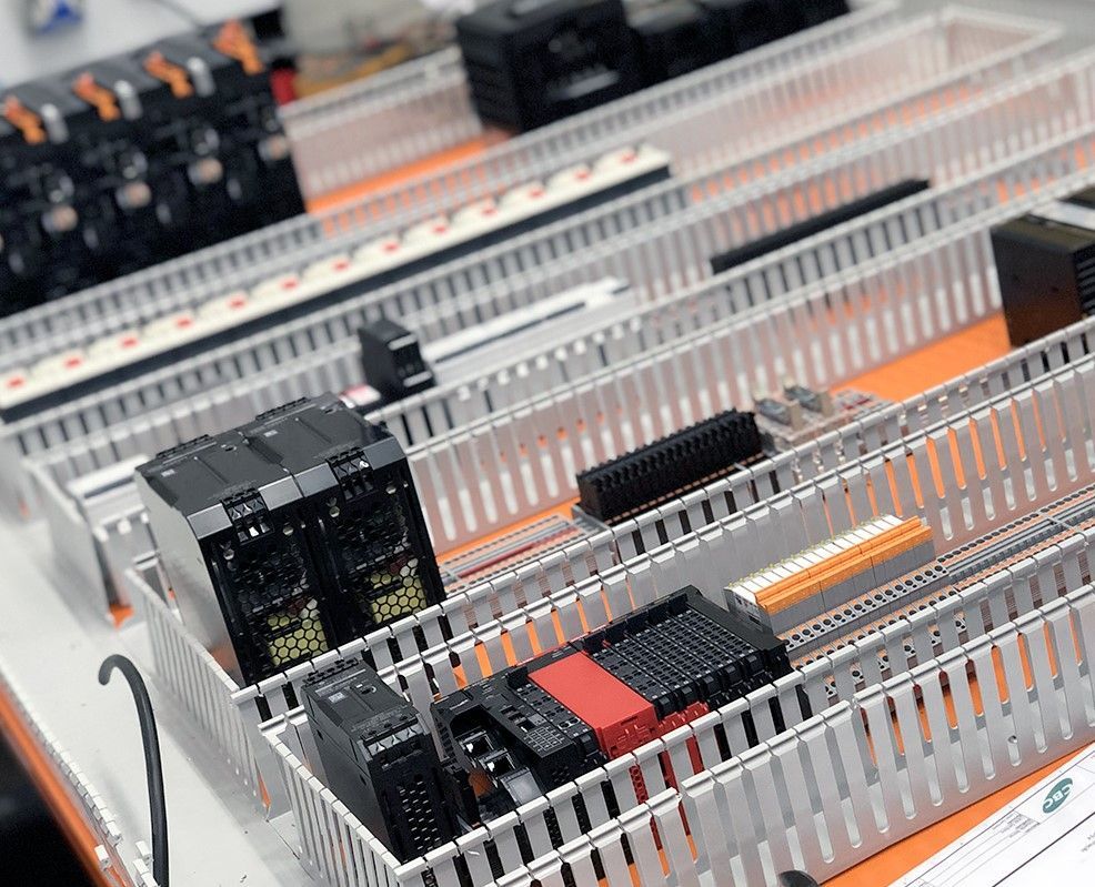 Fileiras de componentes elétricos, incluindo placas de circuito impresso e módulos, em uma caixa metálica segmentada.