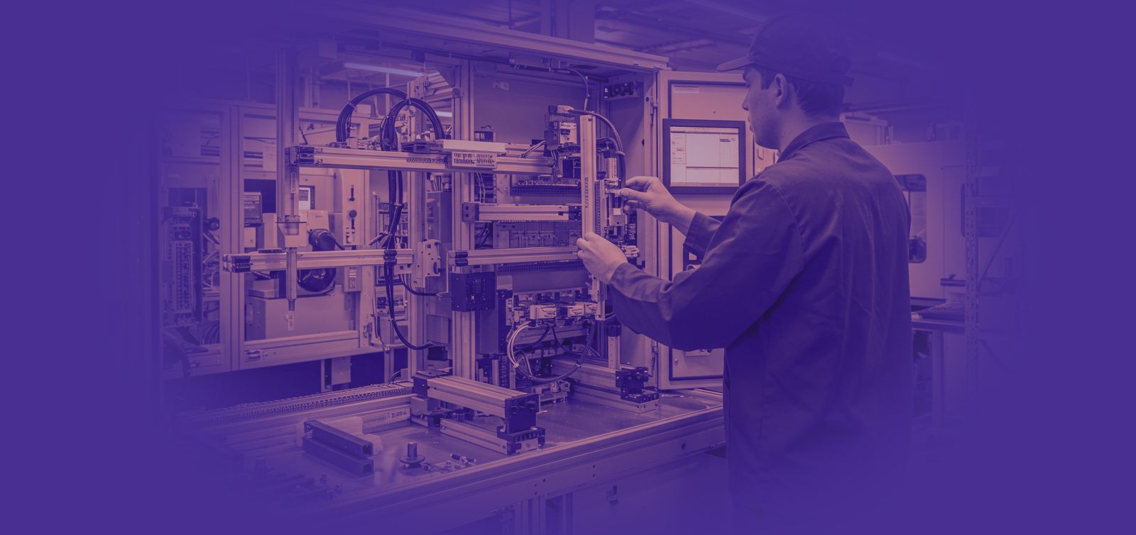 Homem trabalhando em uma máquina em uma oficina, verificando uma tela. Tons de azul e roxo.
