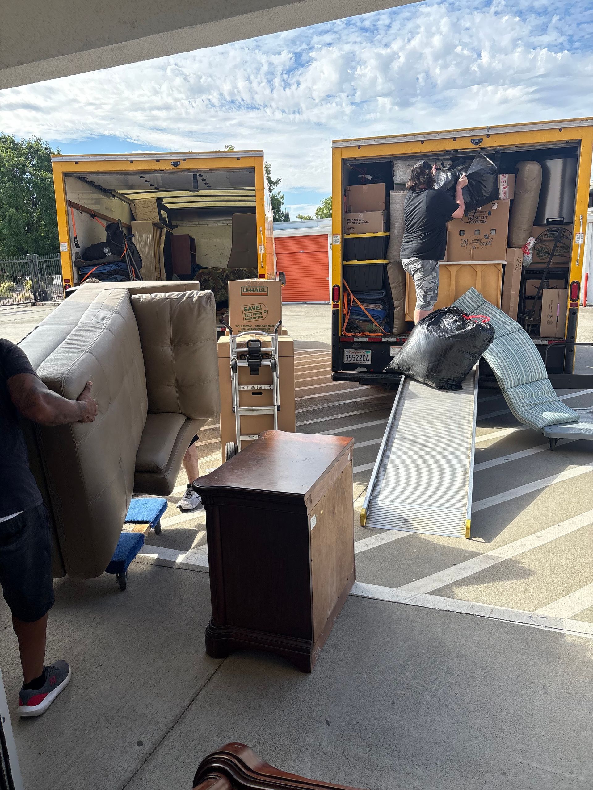 Two moving trucks loaded with furniture and wrapped items in a parking lot