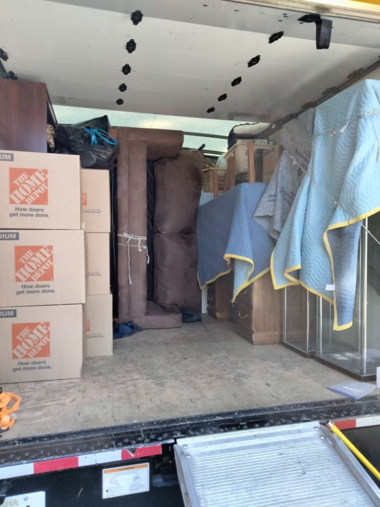 Packed moving truck with boxes, furniture, and covered items inside the cargo area.