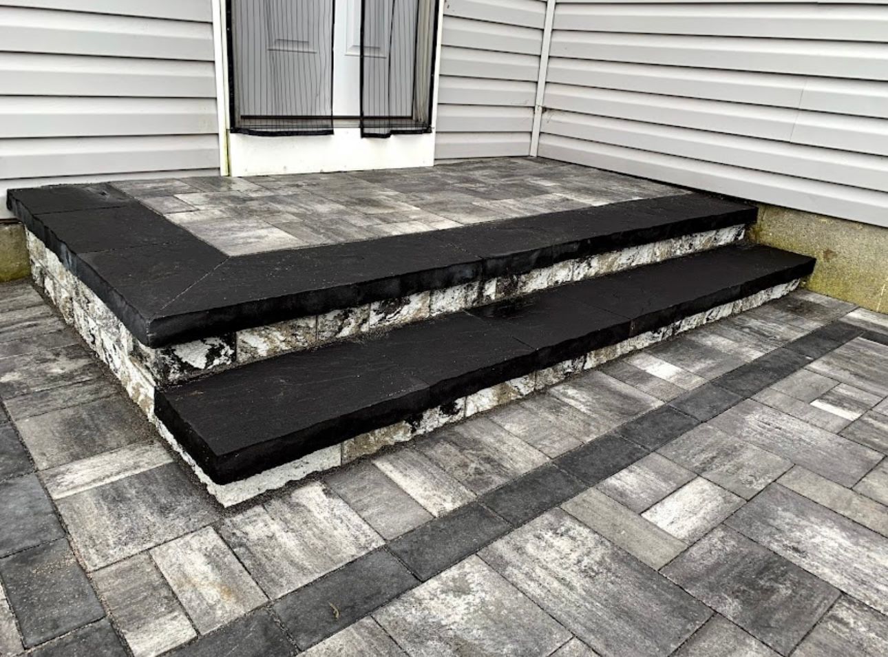 Grey paver stoop with dark step treads and matching patio at a Stonerock project in Terryville, NY