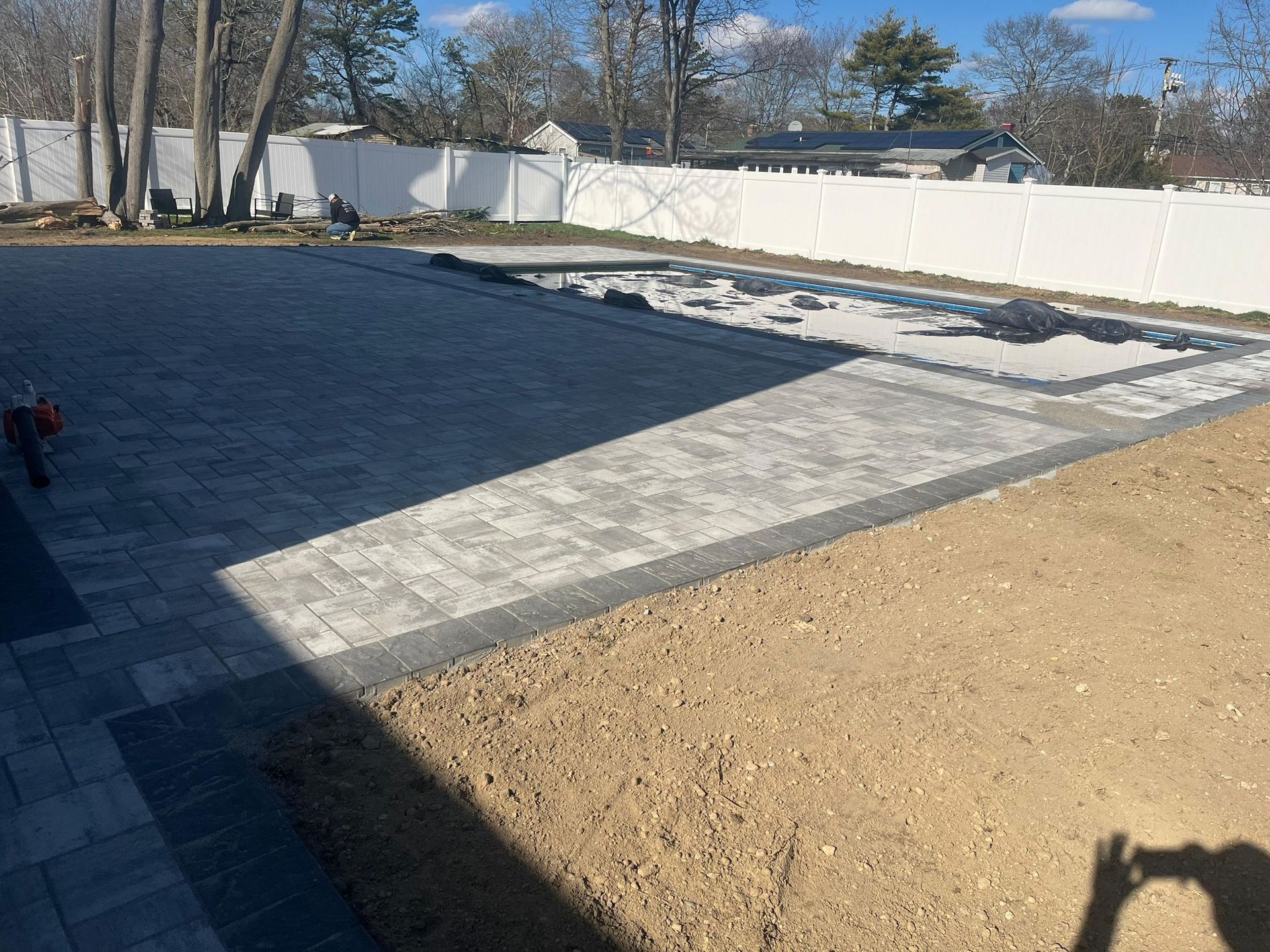 Grey poolside paving with a dark border around a covered swimming pool