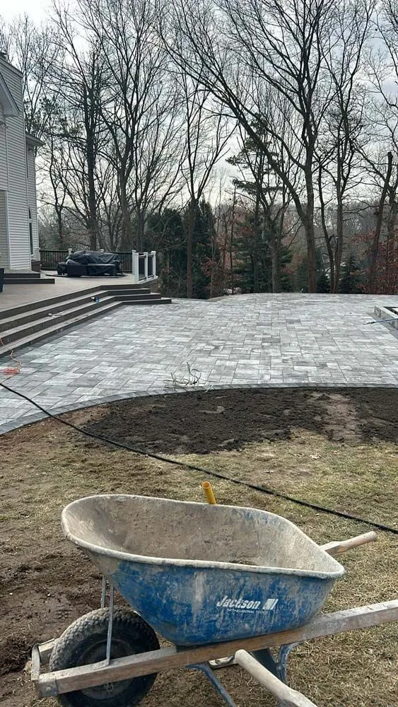 Grey paver patio connected to raised decking by a wide set of steps