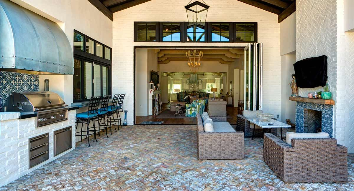 Covered patio design with brick-style paving and an outdoor cooking area