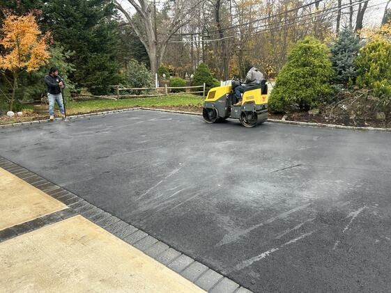 Roller compacting an asphalt driveway during paving work