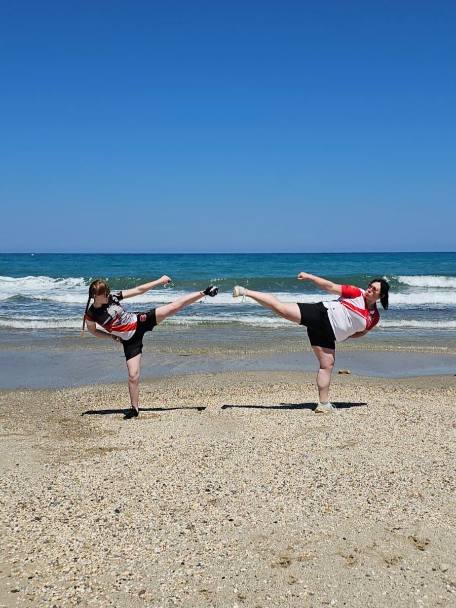Danielle Williams and Ella Barnes side kick on the beach in Crete