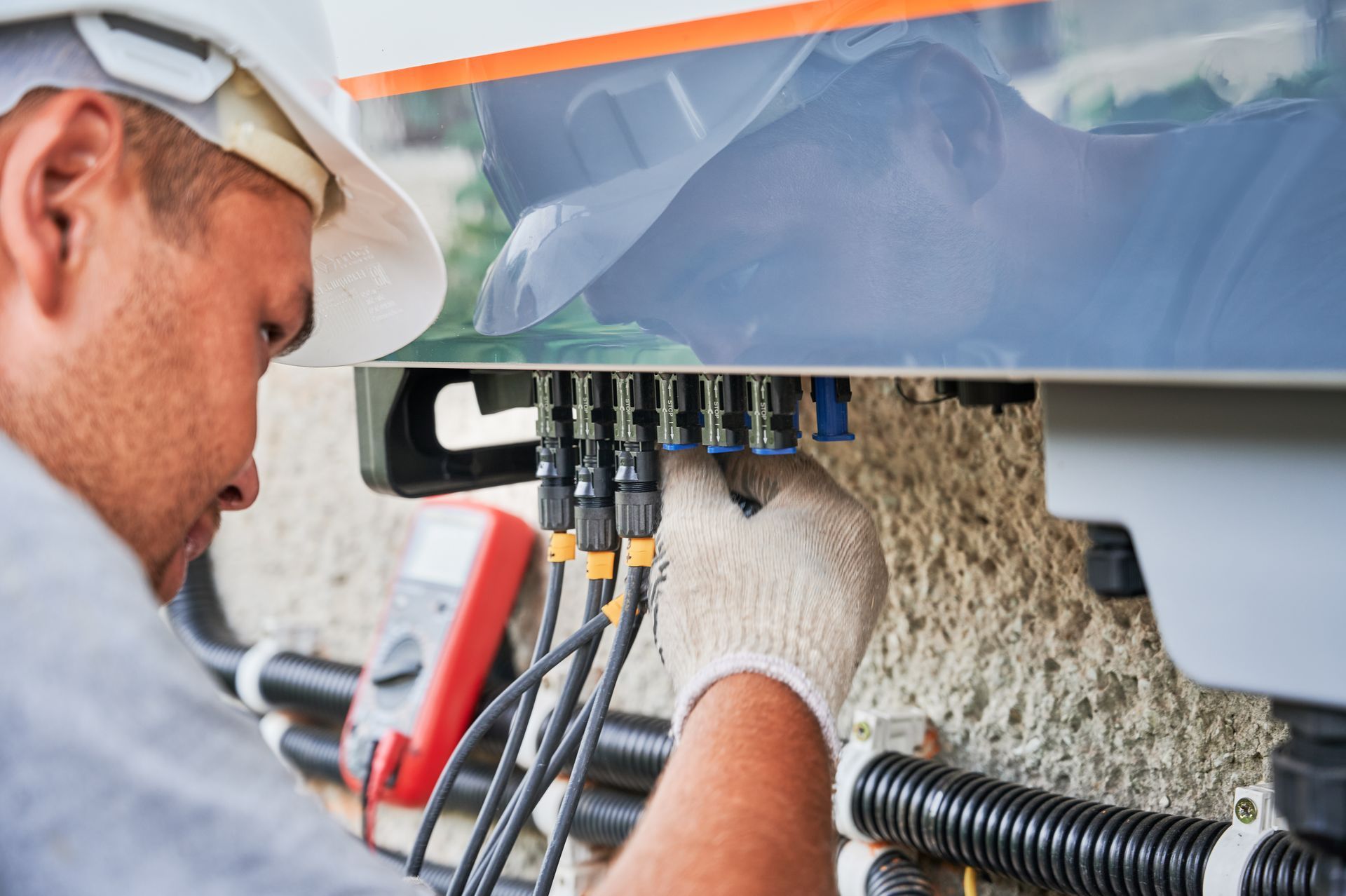 Man electrician installing solar panel system. Inspector in gloves making electrical wiring inverter and electric box. Man electrician installing solar panel system. Inspector in gloves making electrical wiring inverter and electric box.