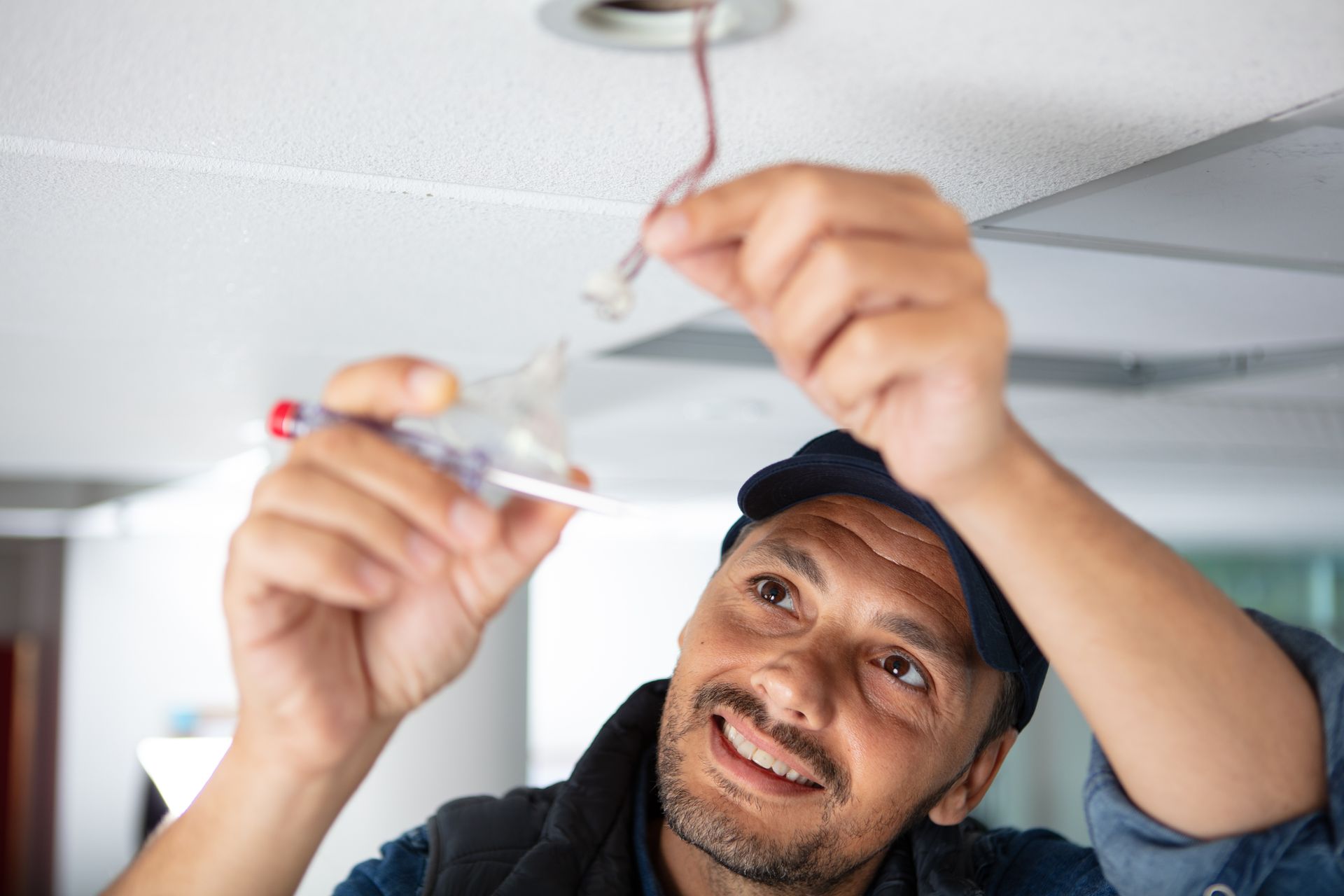 An electrician is fixing a light in the ceiling.