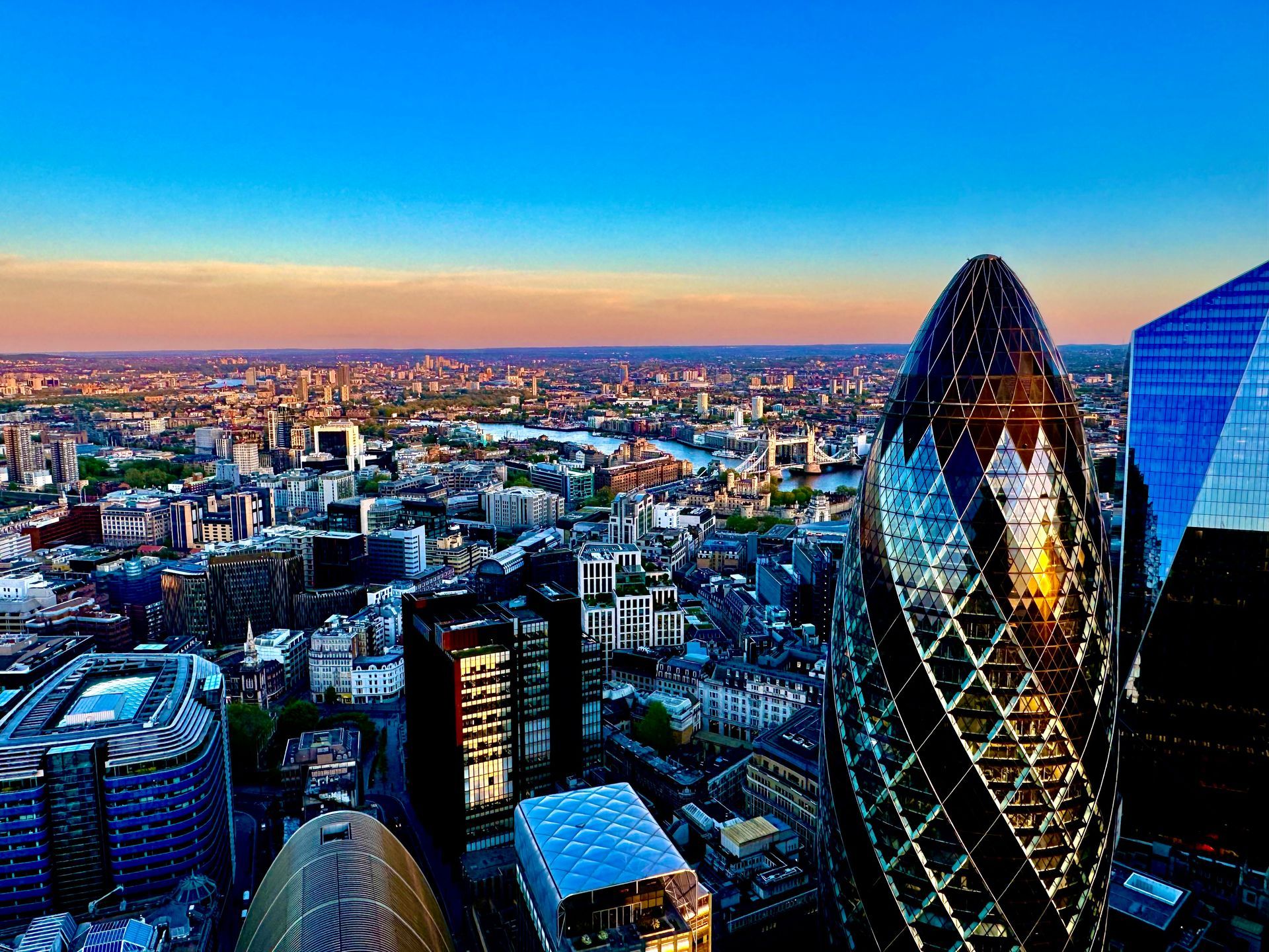 London skyline at sunset, featuring the Gherkin and other skyscrapers.