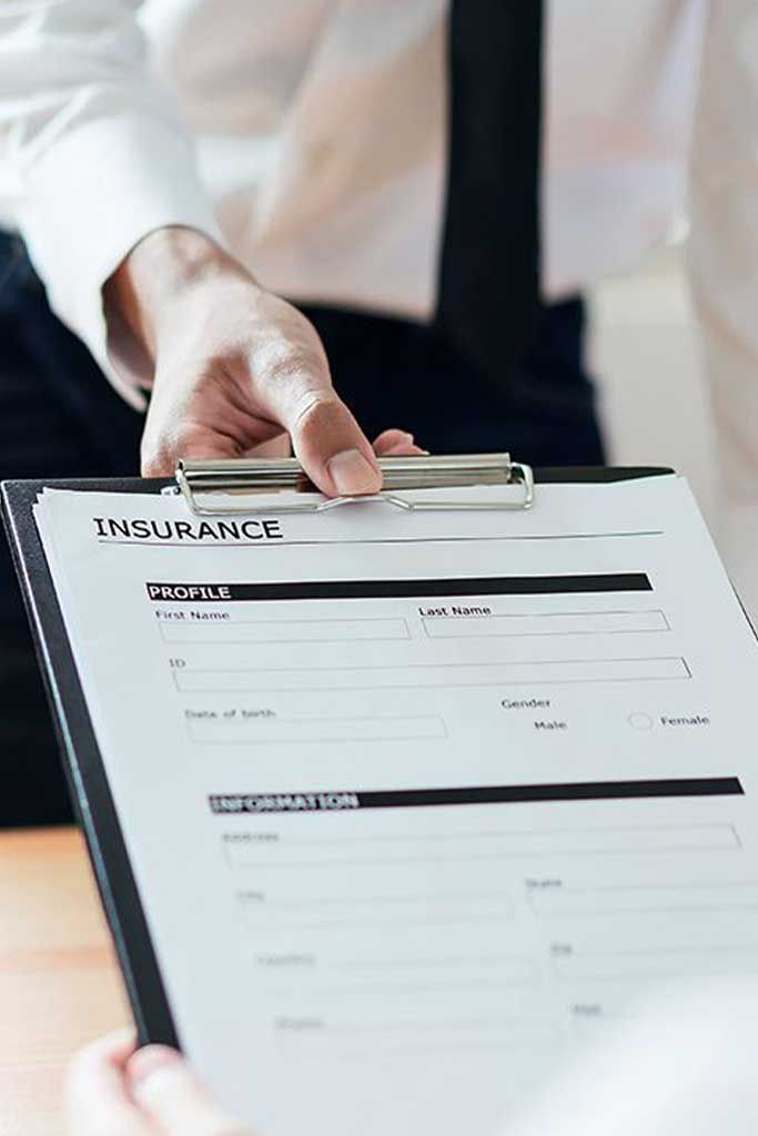 Person holding a clipboard with an insurance form in a bright office setting
