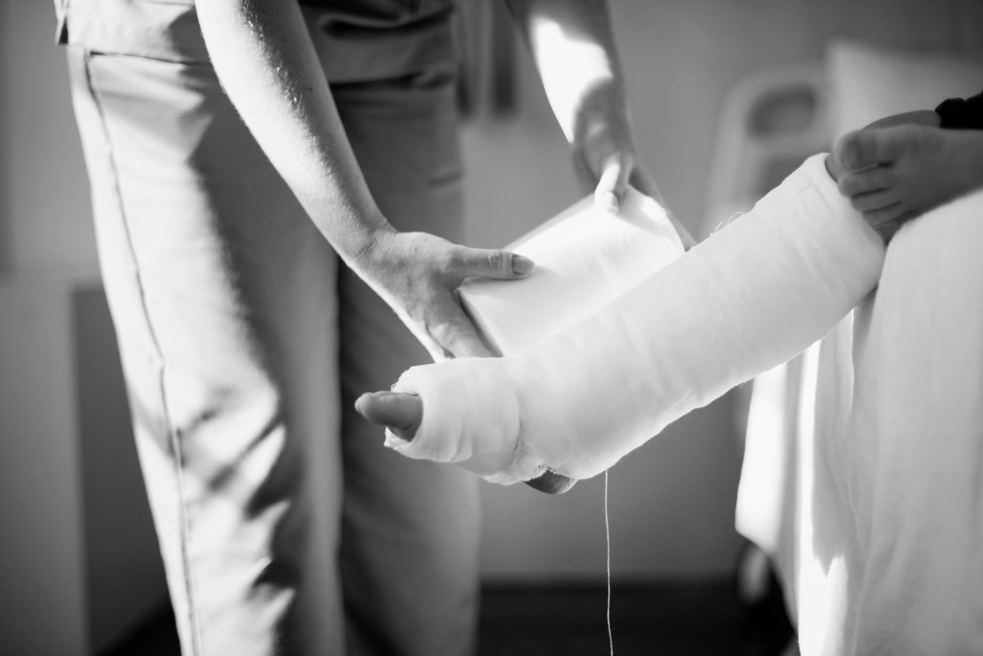 Person wrapping a bandaged leg with a medical cast in a clinical setting