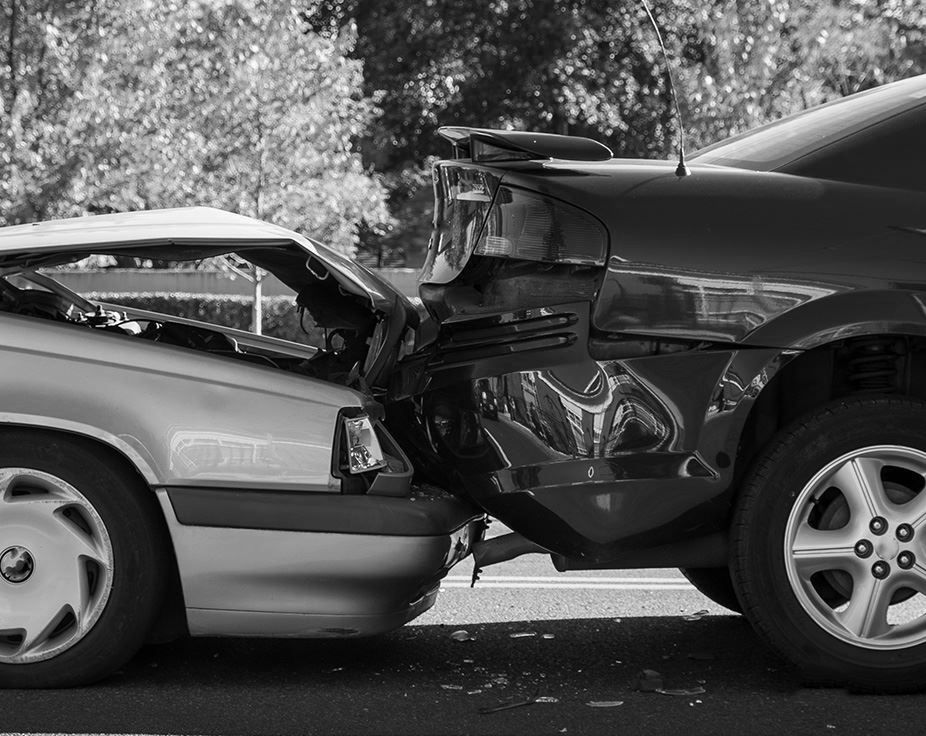 Two cars in a rear-end collision, both front and rear ends crumpled on a road.
