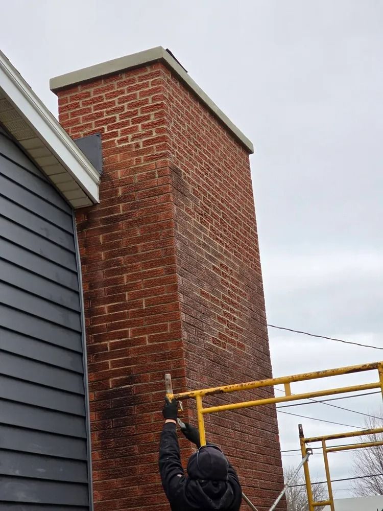 Brick house exterior with arched window, dark brick, tan siding, and white trim against a blue sky.