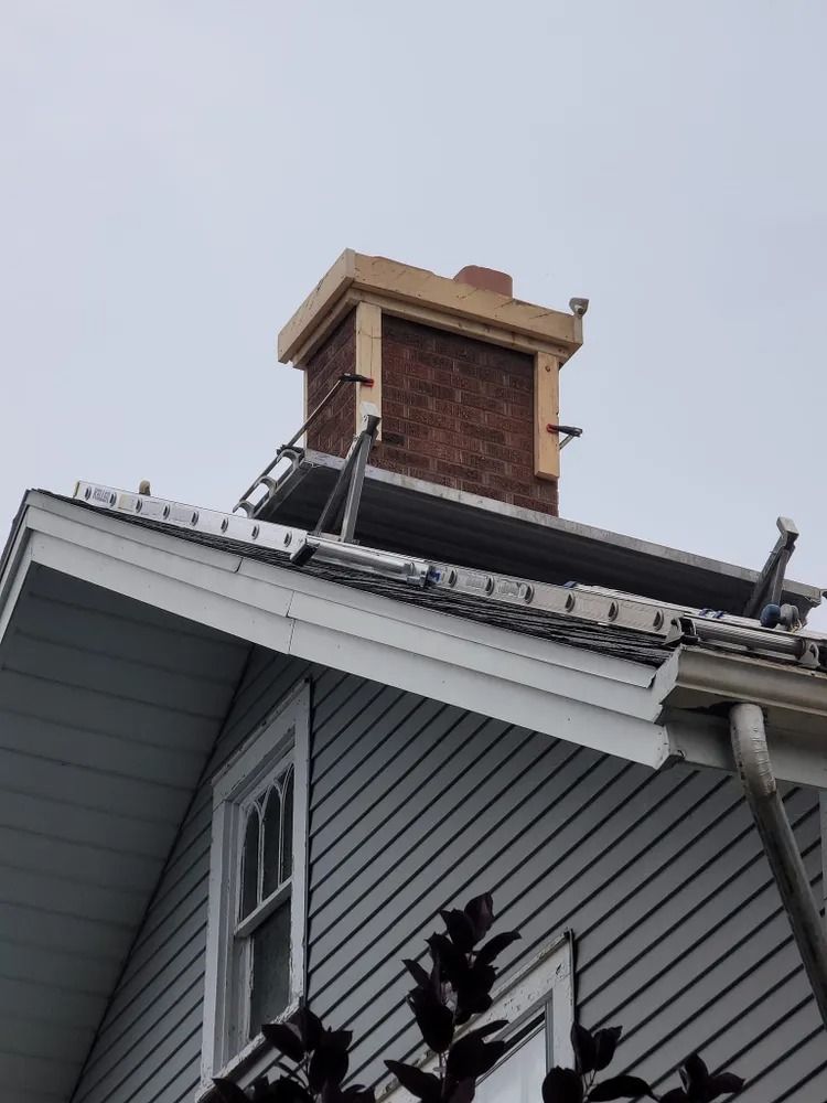 Chimney on a house roof with scaffolding; overcast sky.
