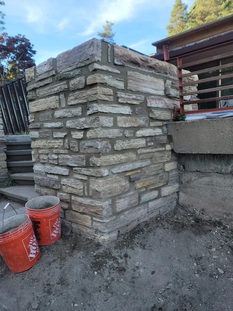 Damaged brick exterior wall under repair. Bricks, debris, tools present. Pink insulation exposed.