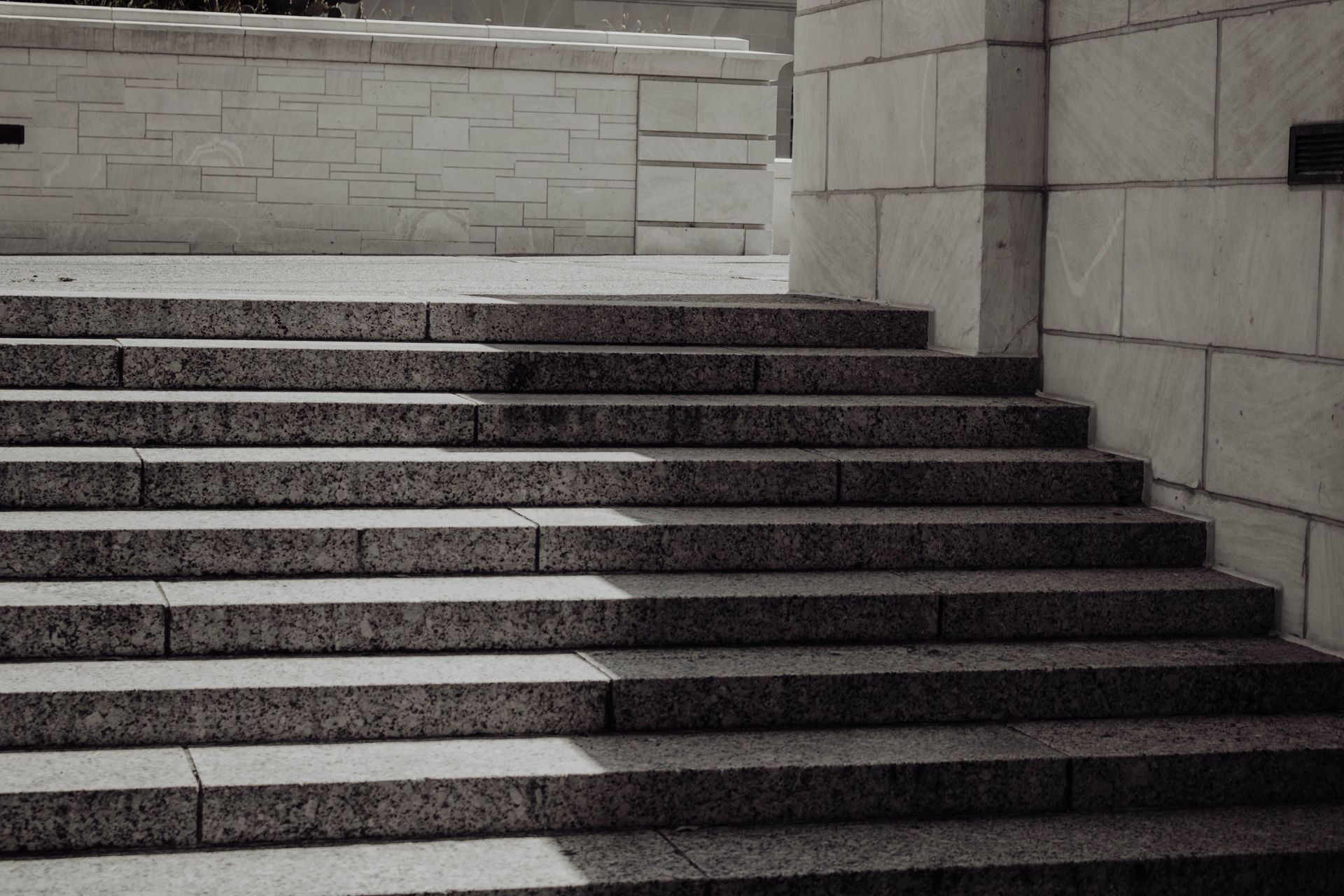 Stone steps leading up to a tiled landing beside a light gray wall.