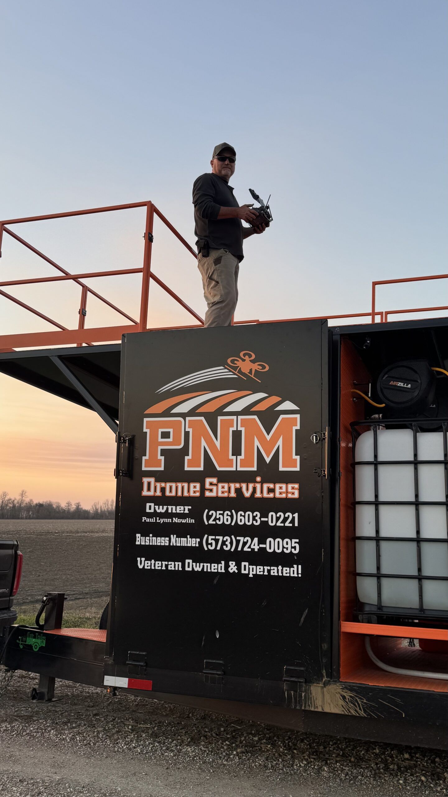 Worker standing on a truck with PNM Drain Services logo and equipment visible