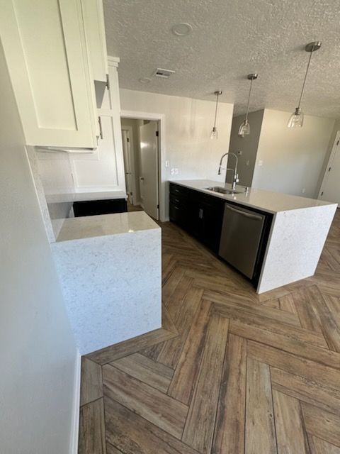 Modern kitchen with white countertops, black cabinets, and wood-look flooring.