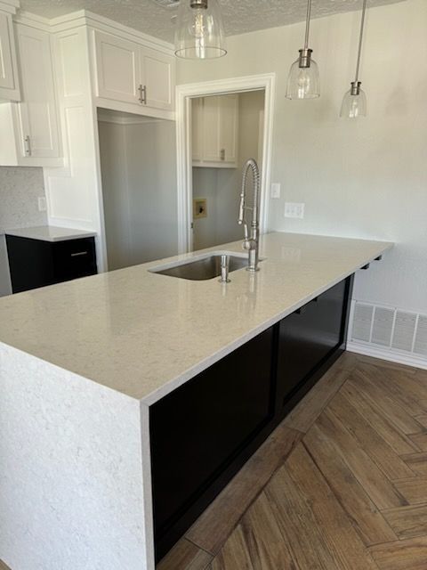 Kitchen with white countertop, dark cabinets, and stainless steel sink.