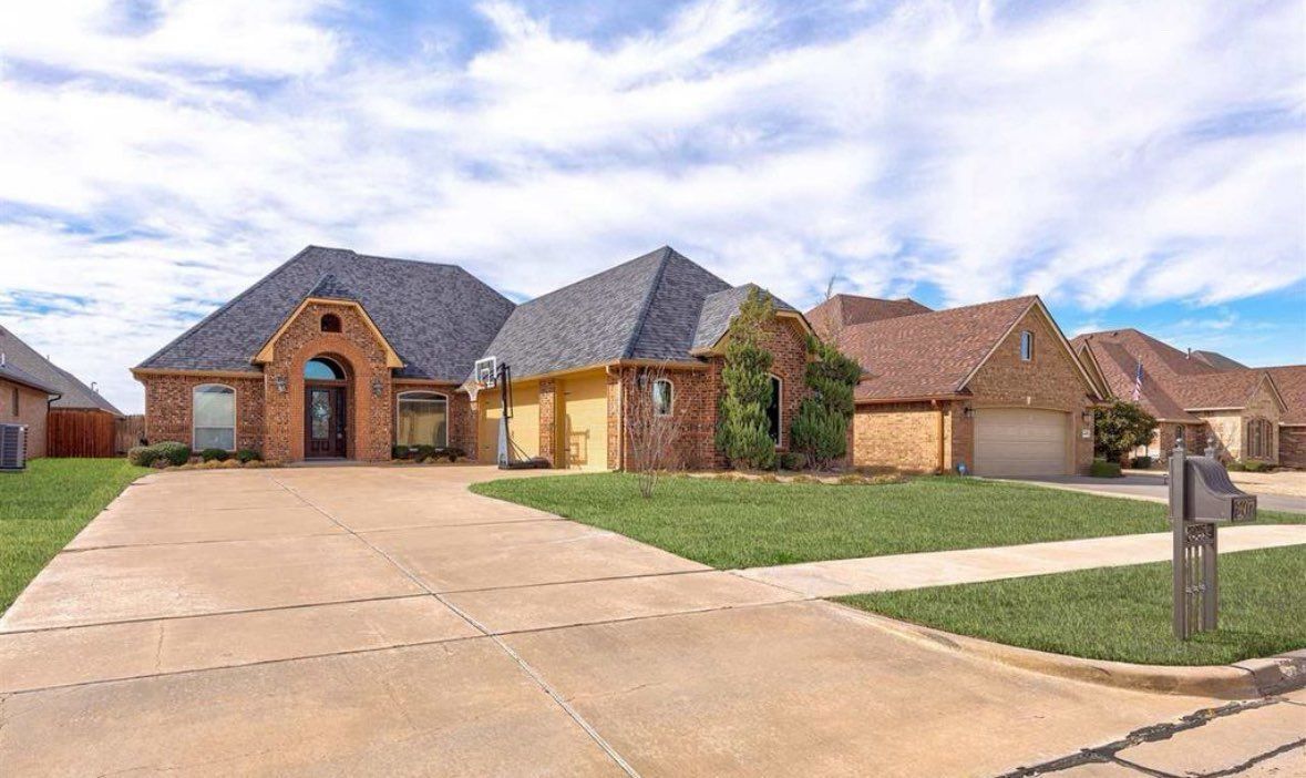 Brick house with driveway, garage, and mailbox on a sunny day.