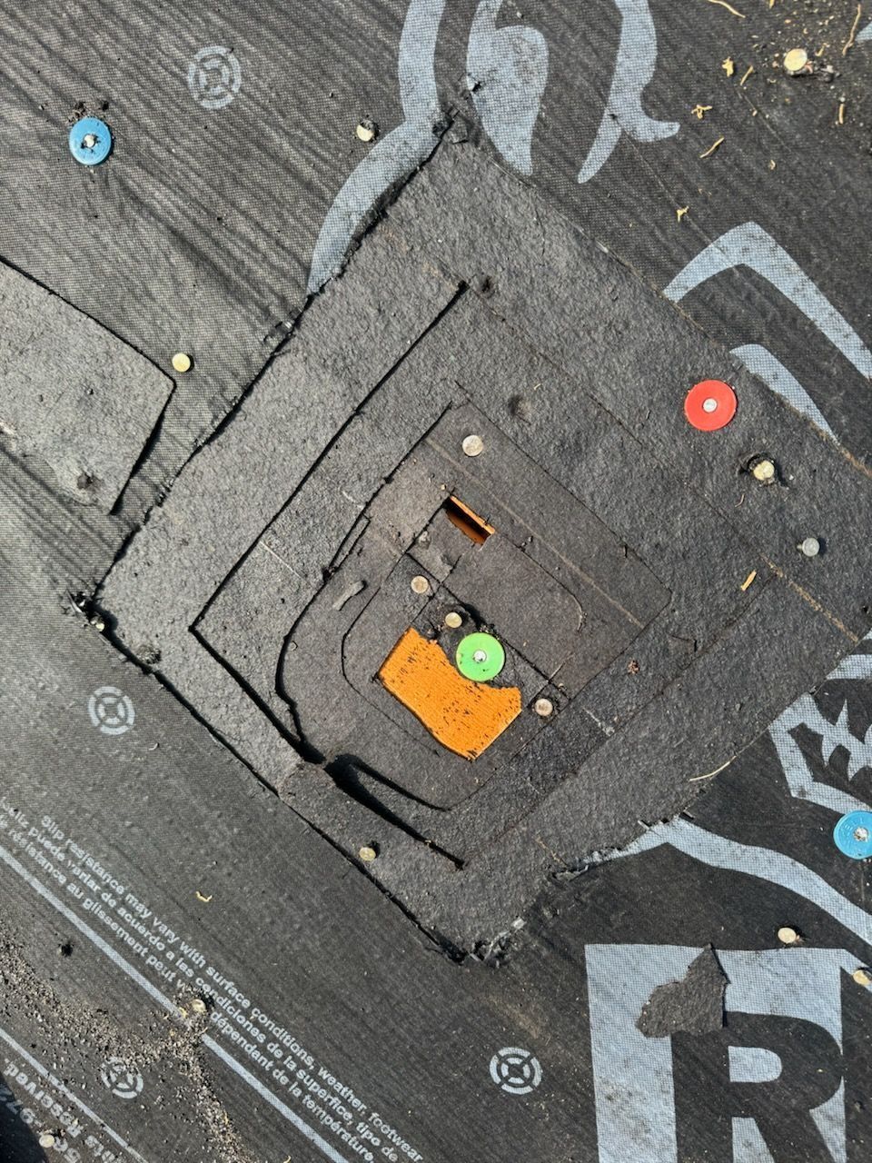 Dark roofing with a nested square cut-out, marked with colored tacks, possibly indicating a repair.