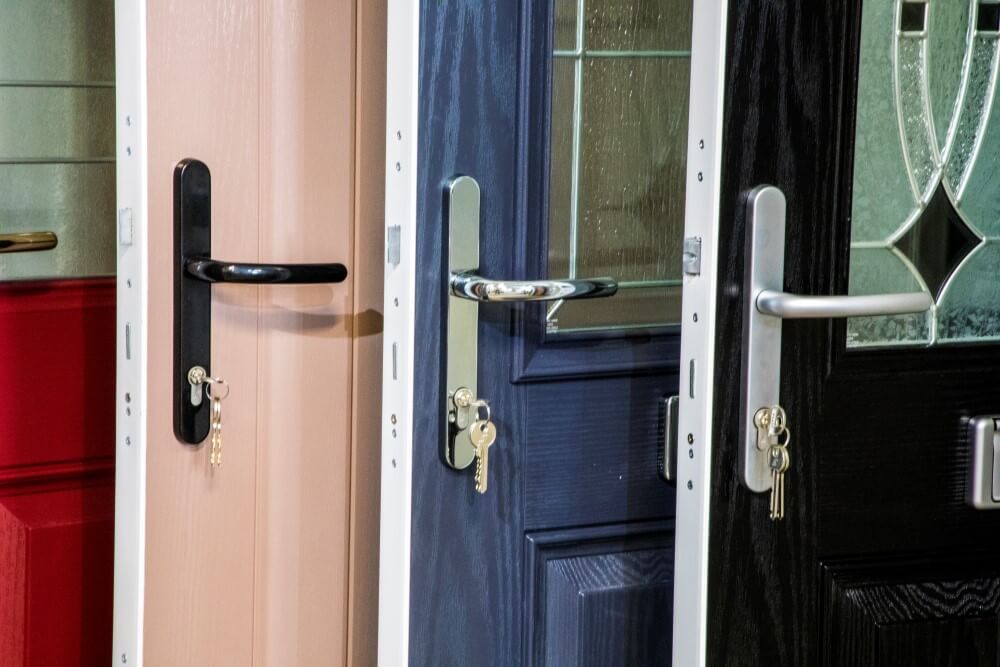 Close-up of three exterior doors: pink, blue, and black. Each has a different style of handle with keys.
