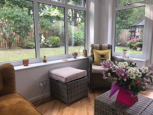 there is a vase of flowers on the table in a well furnished conservatory