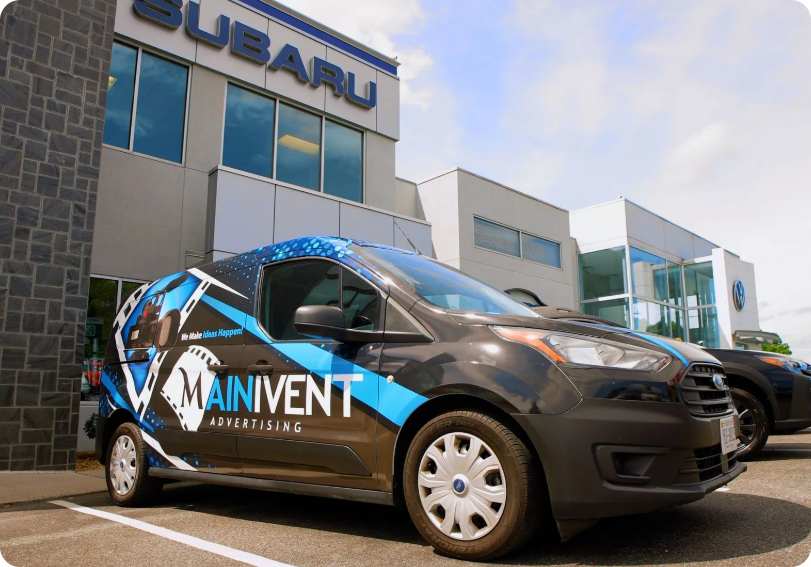 Branded black-and-blue Mainvent car parked outside a Subaru dealership