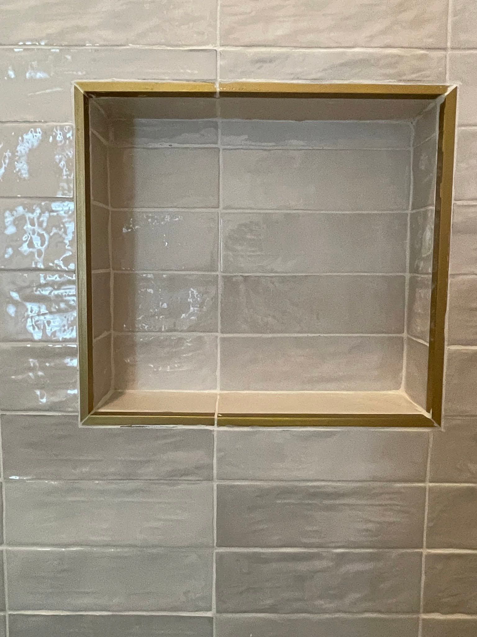 Empty square gold-framed niche in a gray tiled wall