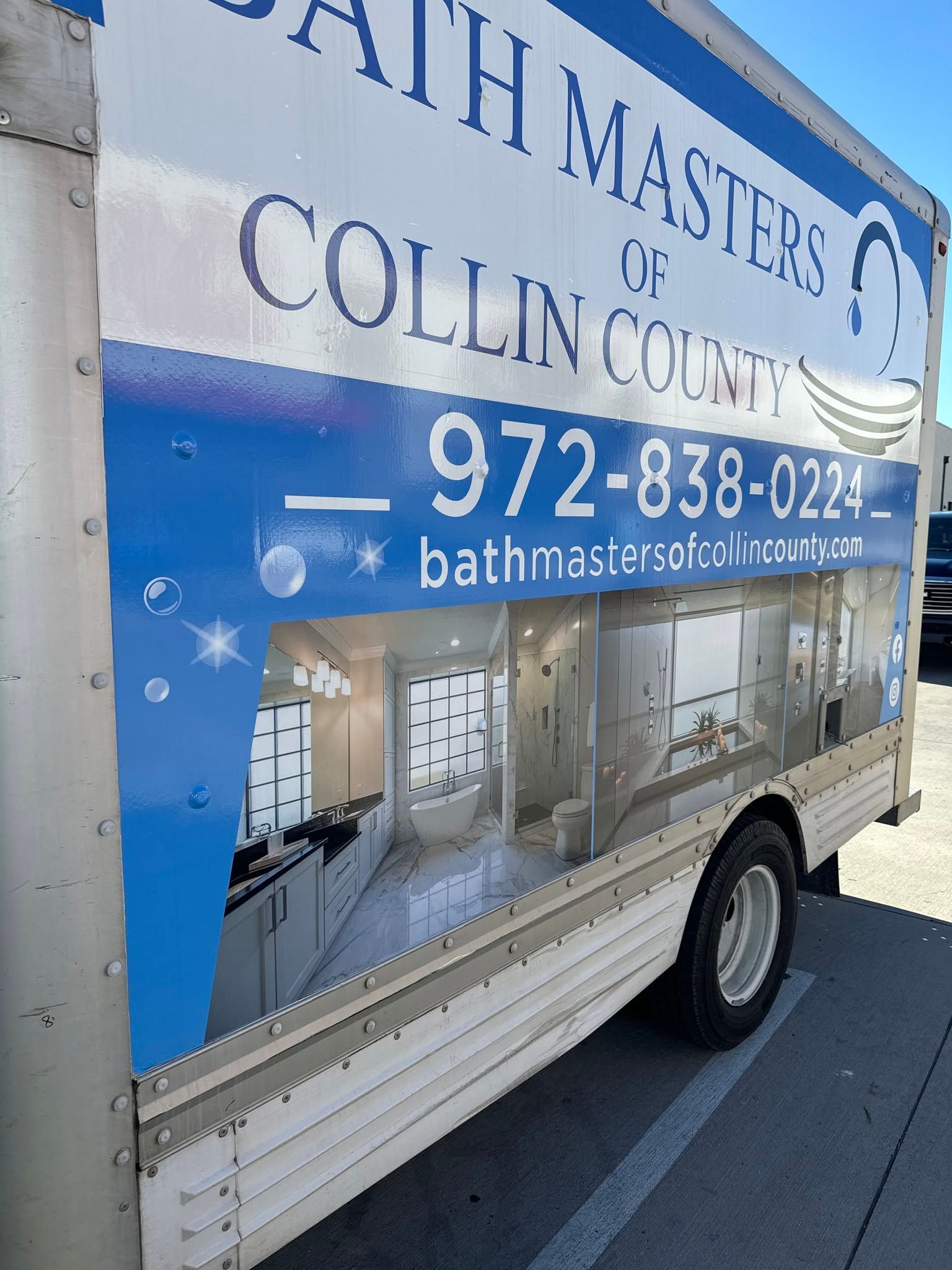 Blue Bath Masters LLC truck with plumbing ad, phone number, and bathroom renovation images parked on a street