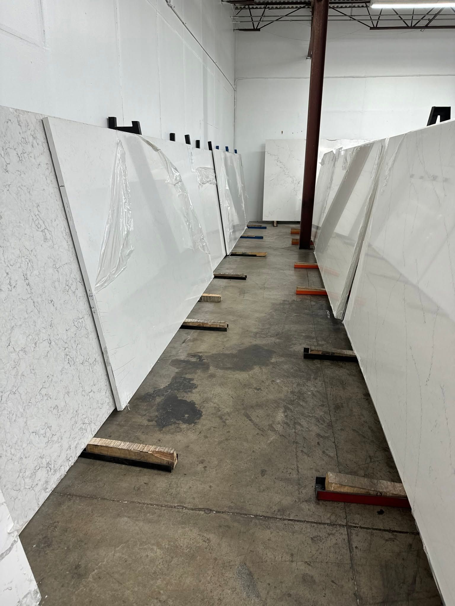 Empty warehouse aisle with large white panels leaning against both walls and wooden blocks on the floor