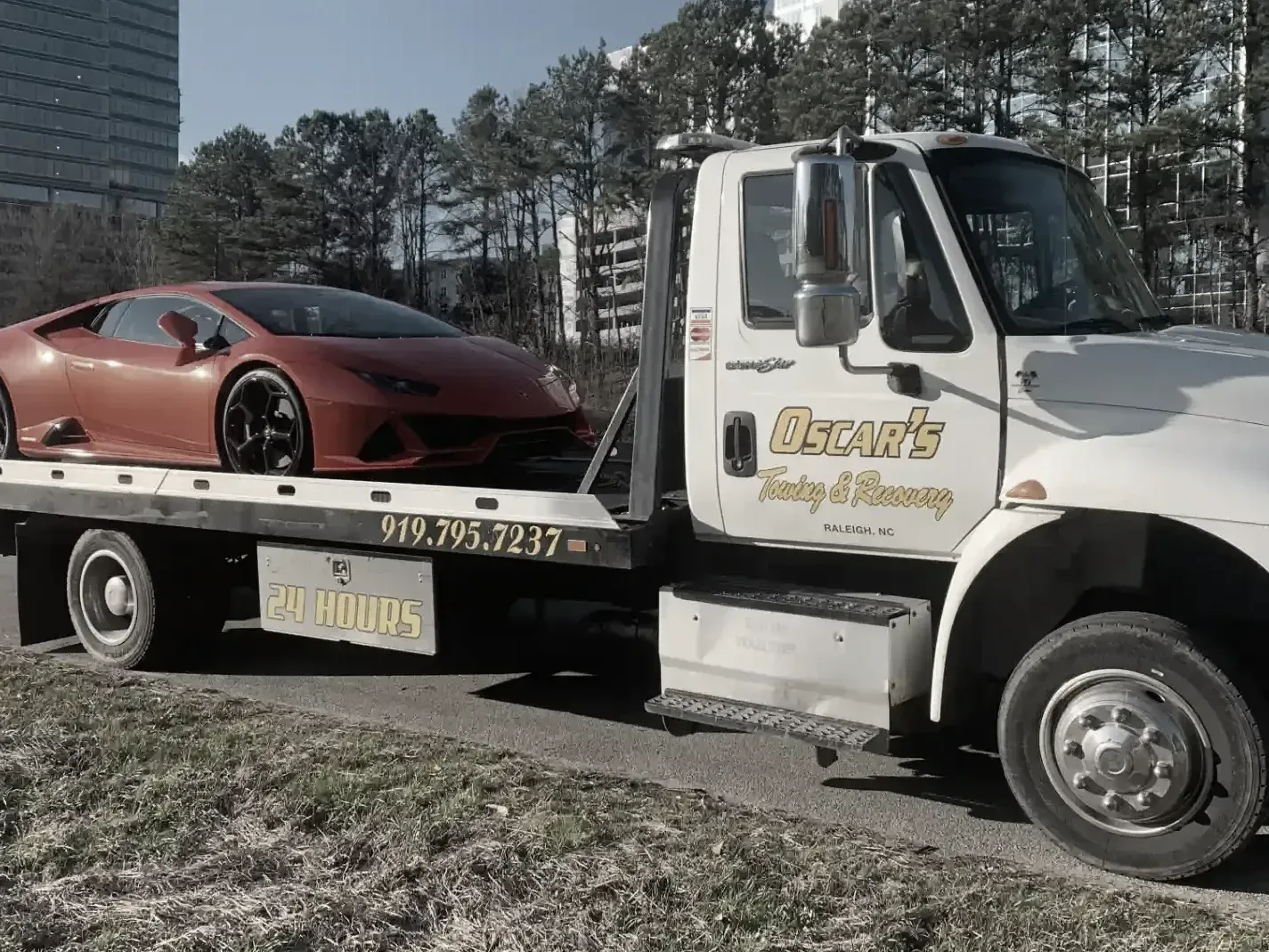 A tow truck is carrying a red sports car on the back.