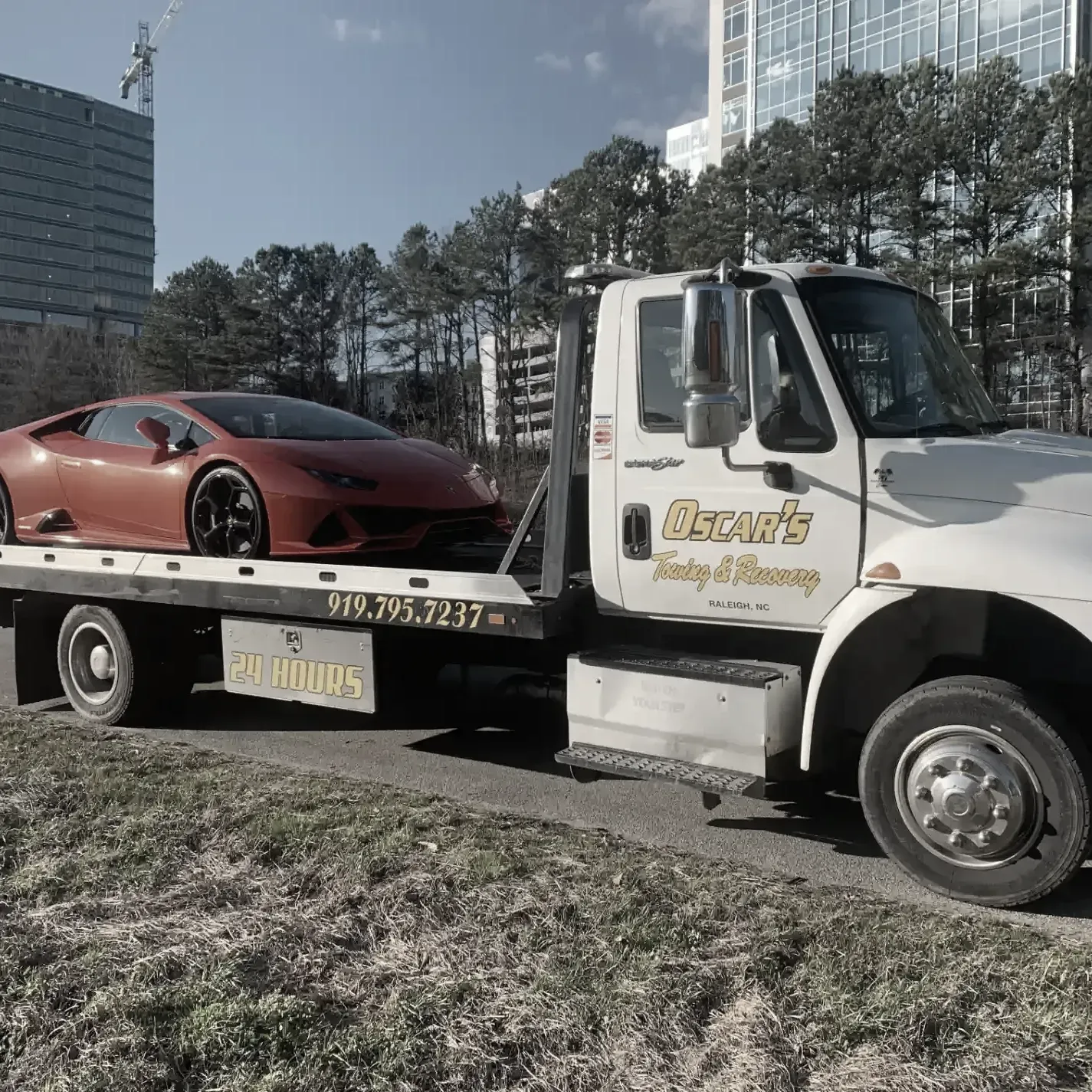 A tow truck with a red sports car on the back of it