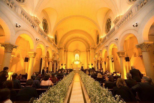 Um grupo de pessoas está sentado em uma igreja assistindo a uma cerimônia de casamento.