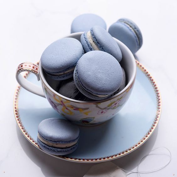 Uma xícara cheia de macarons azuis em um pires