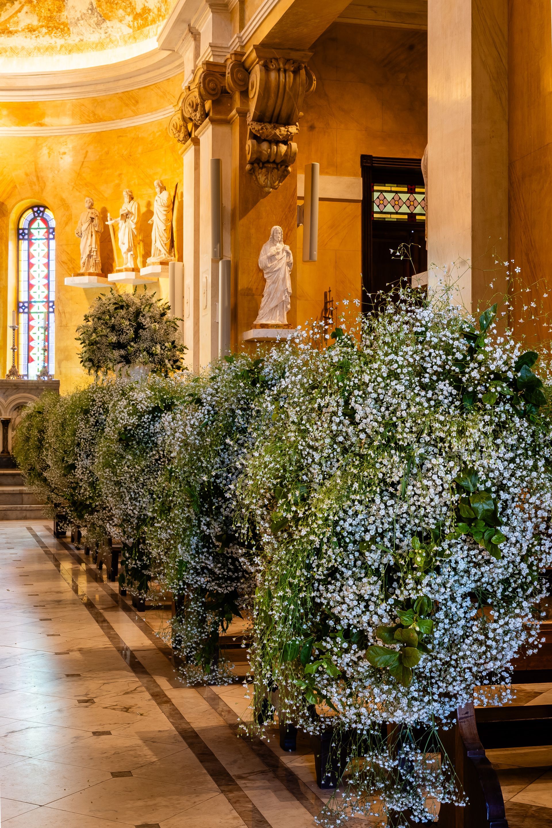 Uma fileira de bancos em uma igreja decorada com mosquitinhos e folhagens.