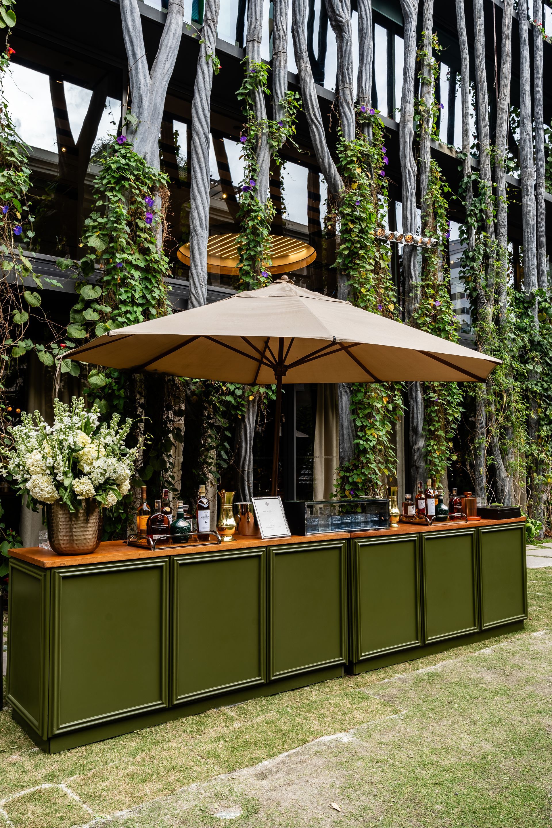 Um longo bar com guarda-sóis e flores em frente a um prédio.