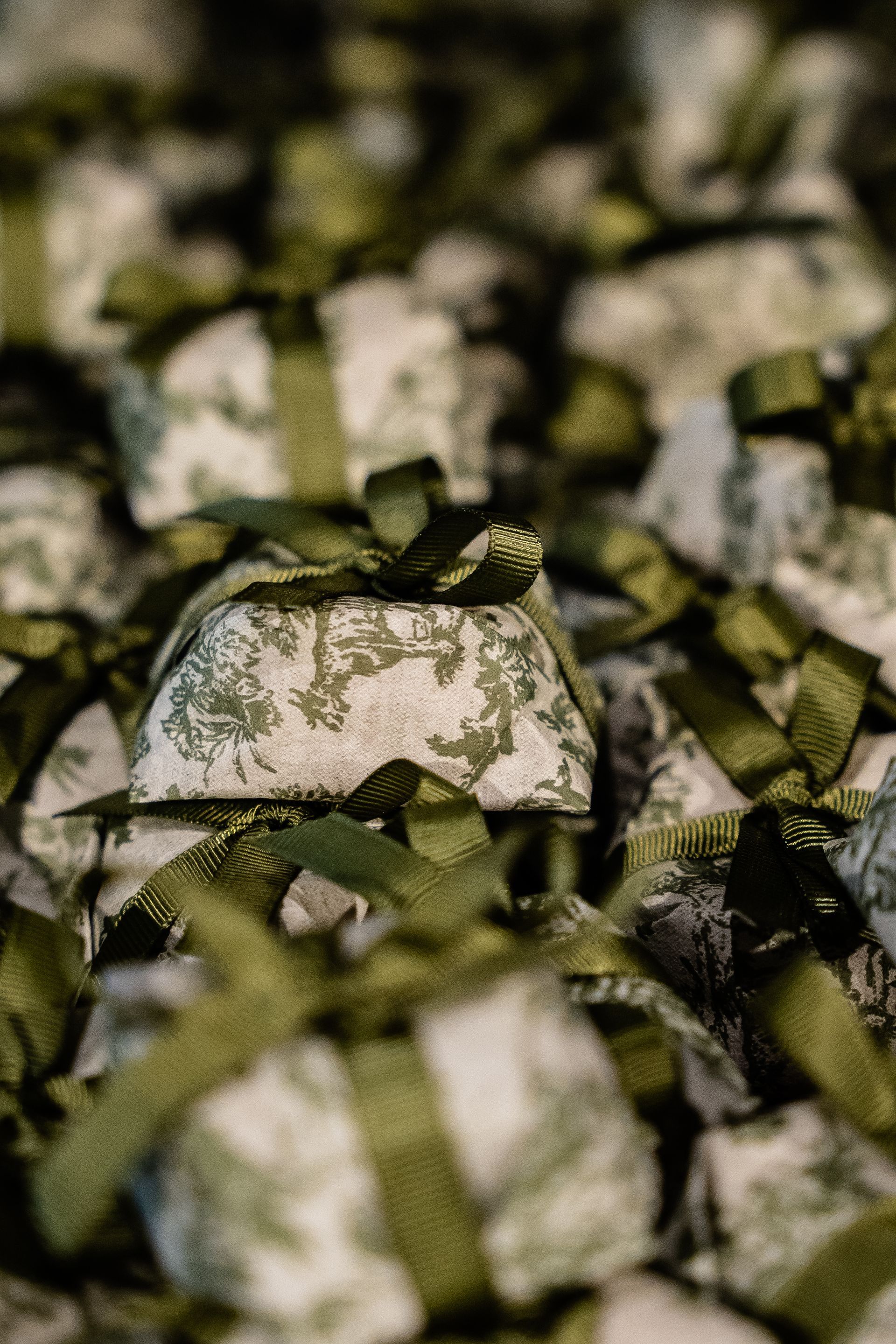 Um close de uma pilha de presentes embrulhados com fitas verdes.