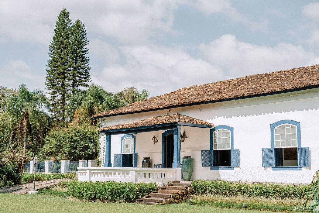 Uma casa branca com telhado de telhas e persianas azuis