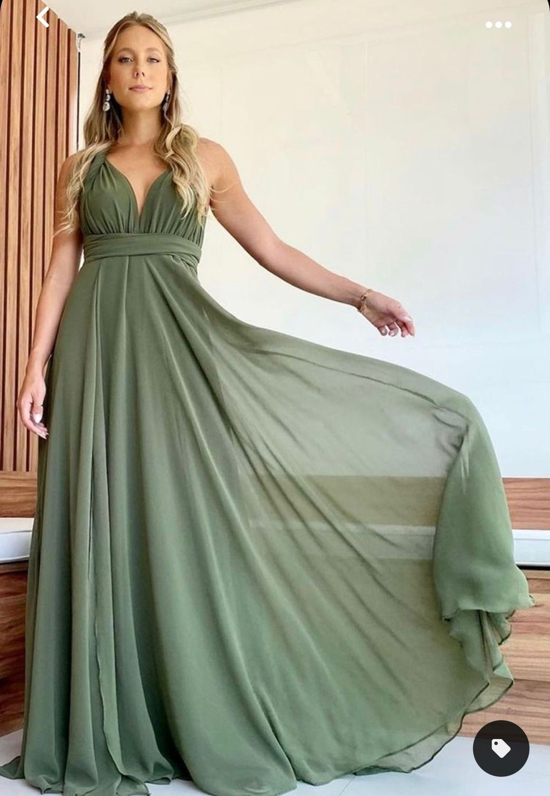 Uma mulher está usando um vestido verde e está parada em frente a uma parede de madeira.