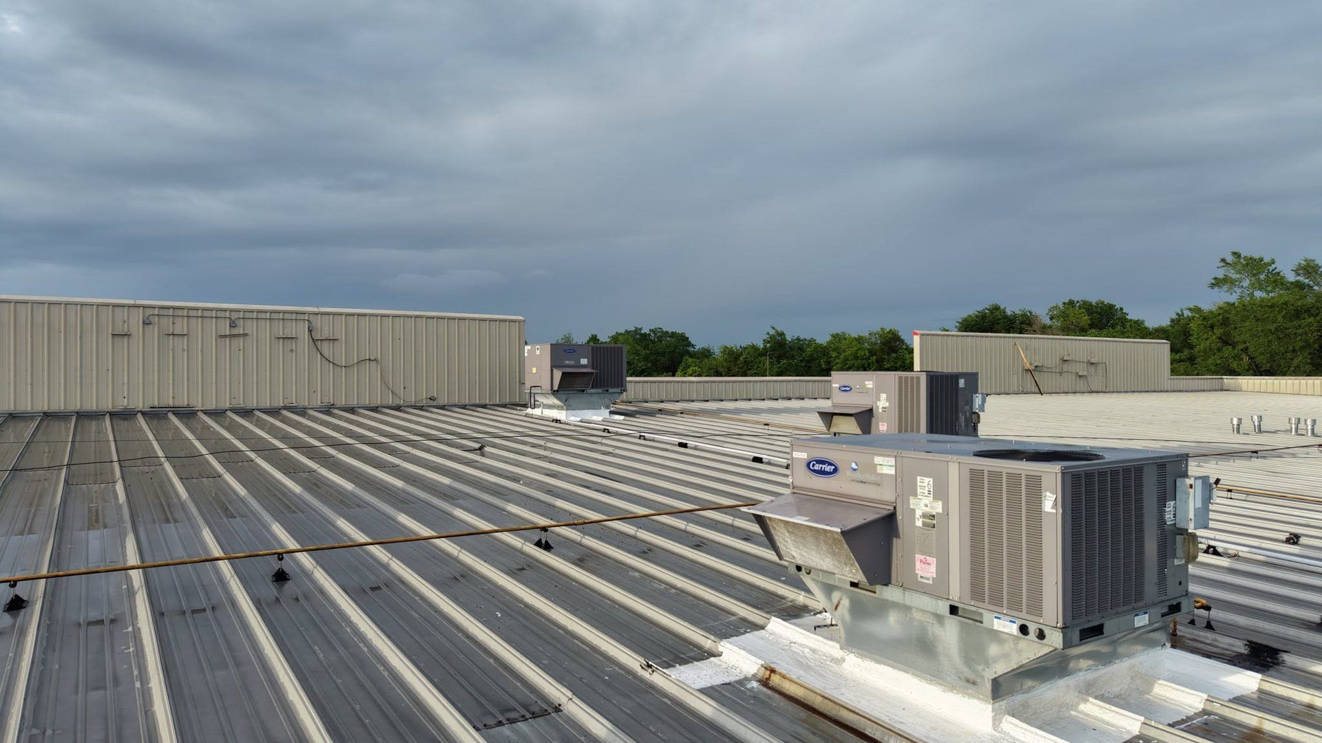 Rooftop with rows of metal panels and HVAC units under a cloudy sky