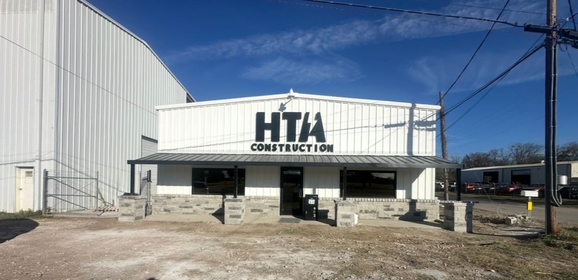 HTA Construction storefront with white exterior and large sign under a blue sky