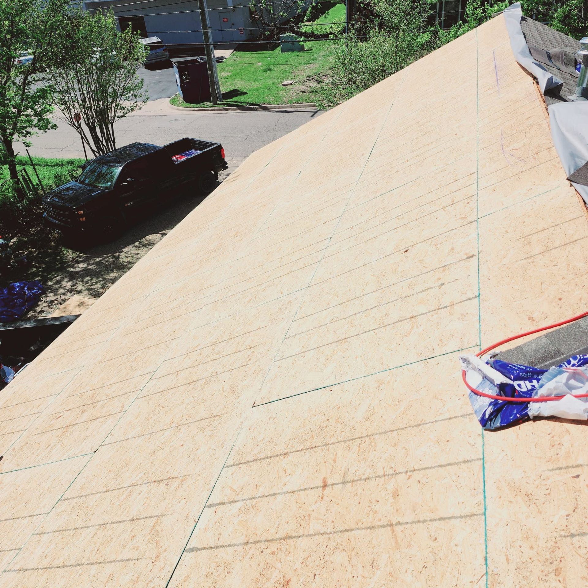 Roof under construction with plywood sheathing and a measuring line, viewed from above.