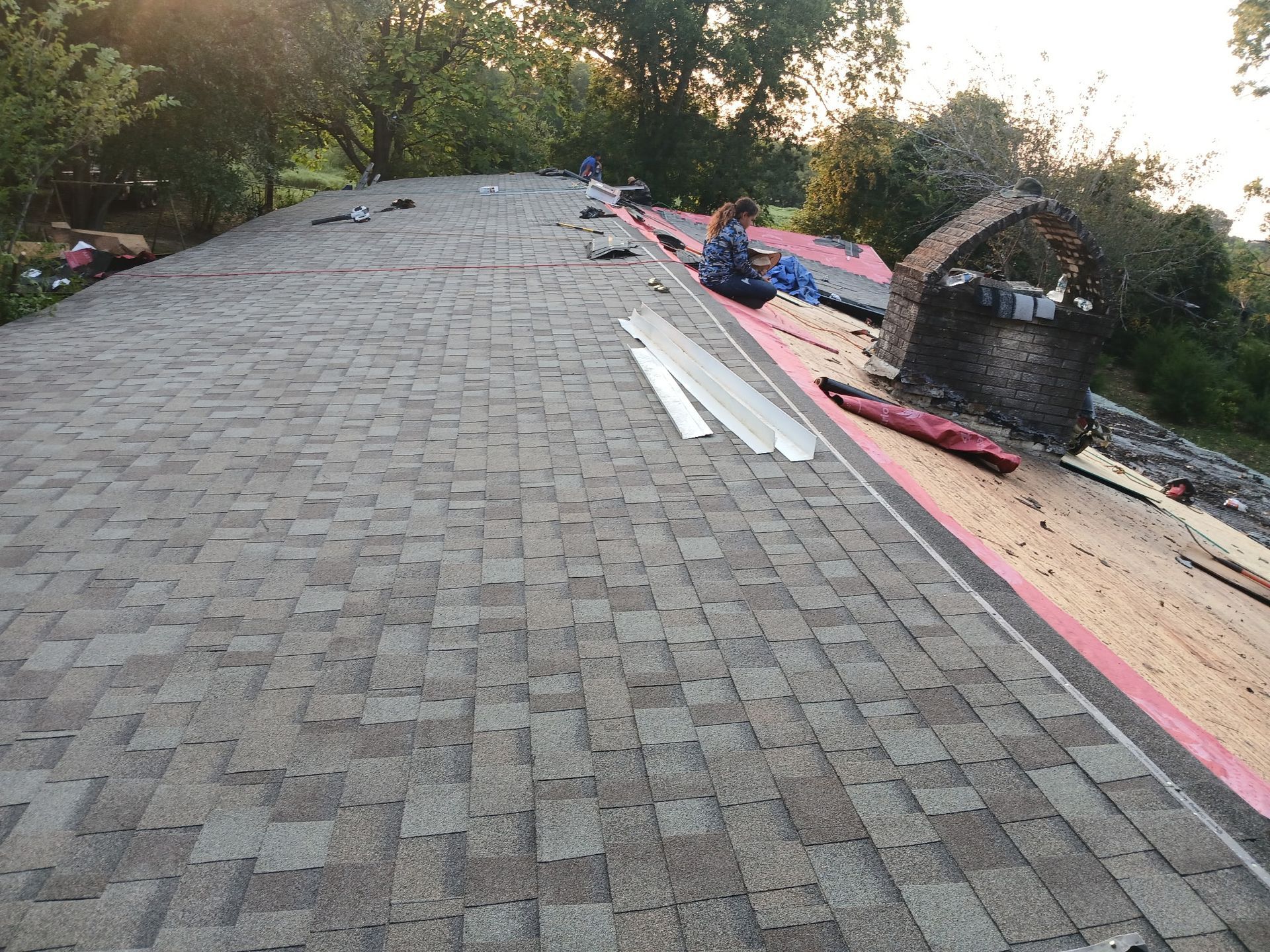 Roof shingles damaged and burned, with debris and tools scattered along the edge of the roof.