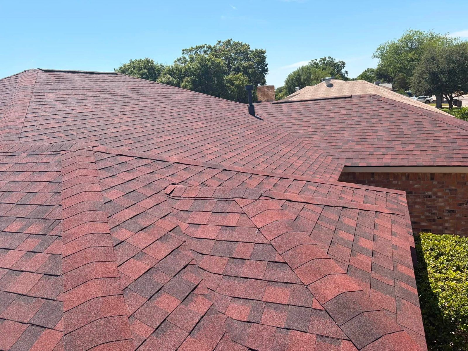 Red shingle roof with a visible ridge and trees in the background