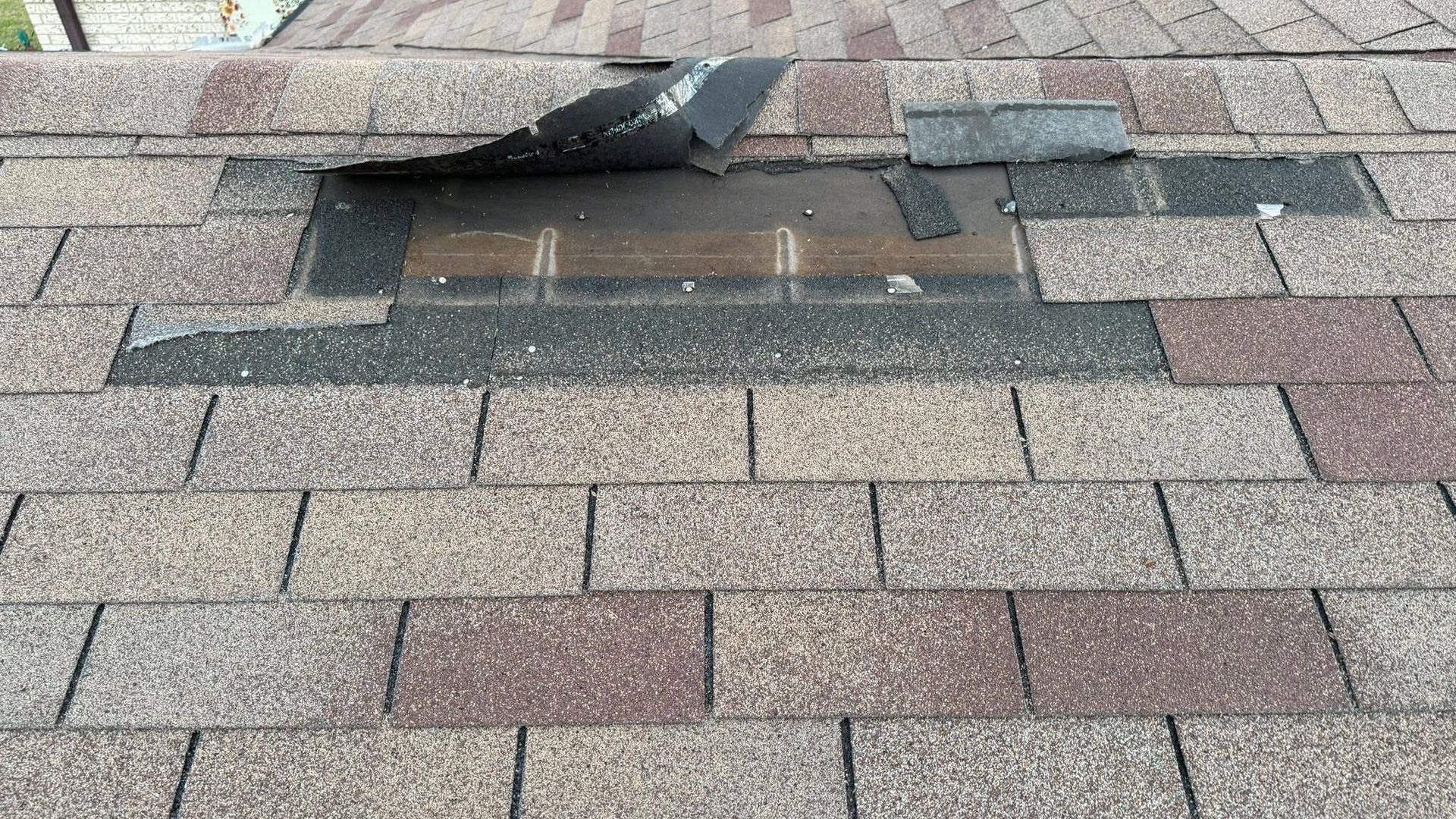 Damaged shingle roof with a sagging, open section near the ridge