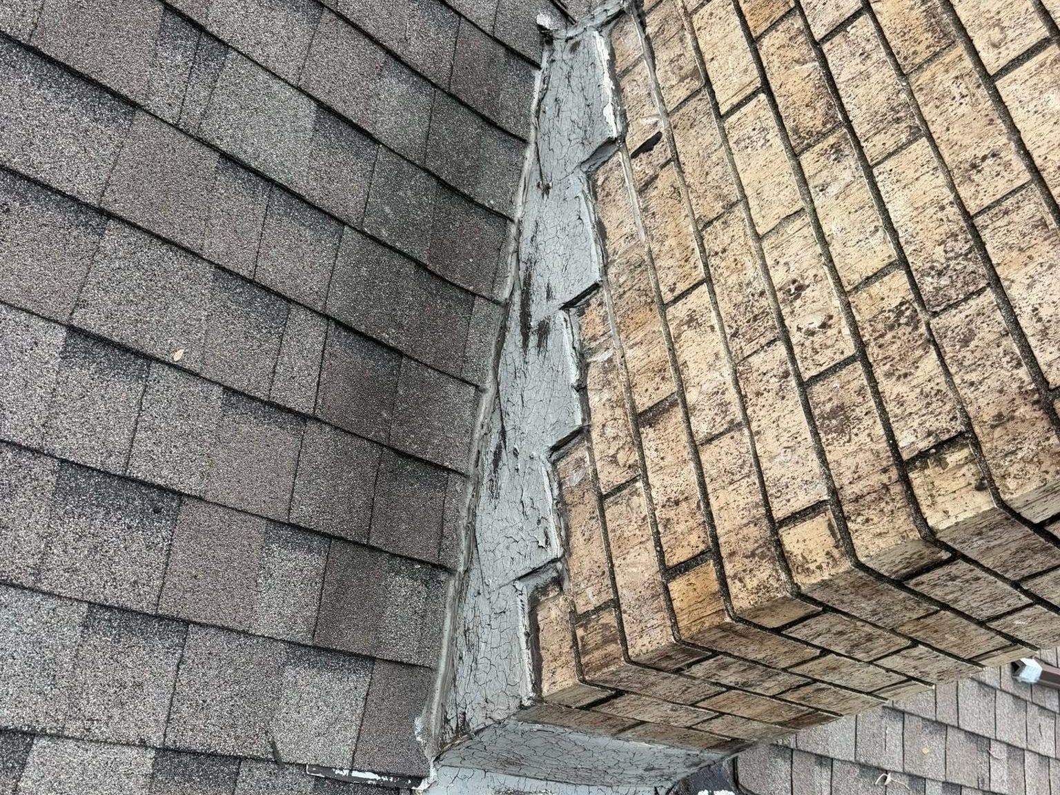 Damaged roof shingles with a large crack between two roof sections